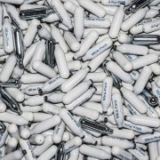 A pile of white and silver Nitrous Oxide canisters